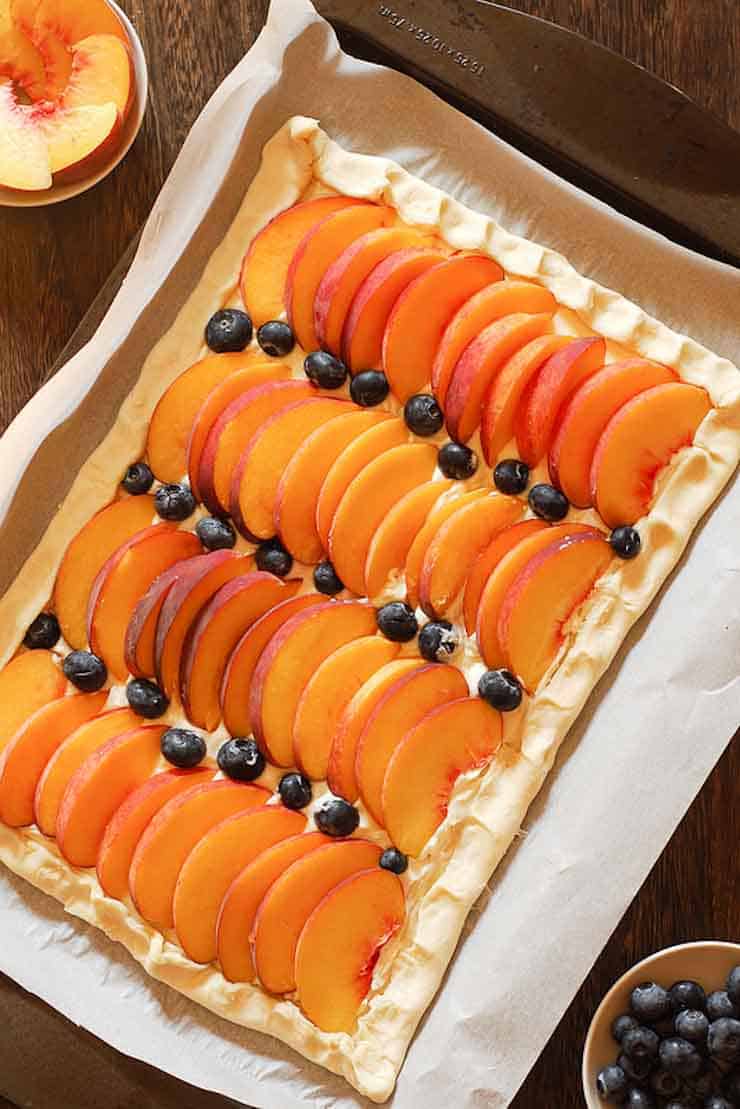 Sliced peaches and blueberries on a baking sheet