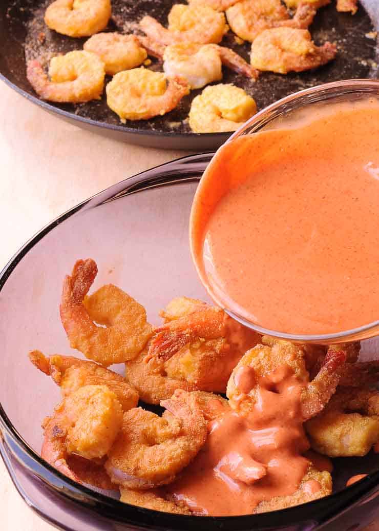 Dynamite sauce being poured on top of the shrimp