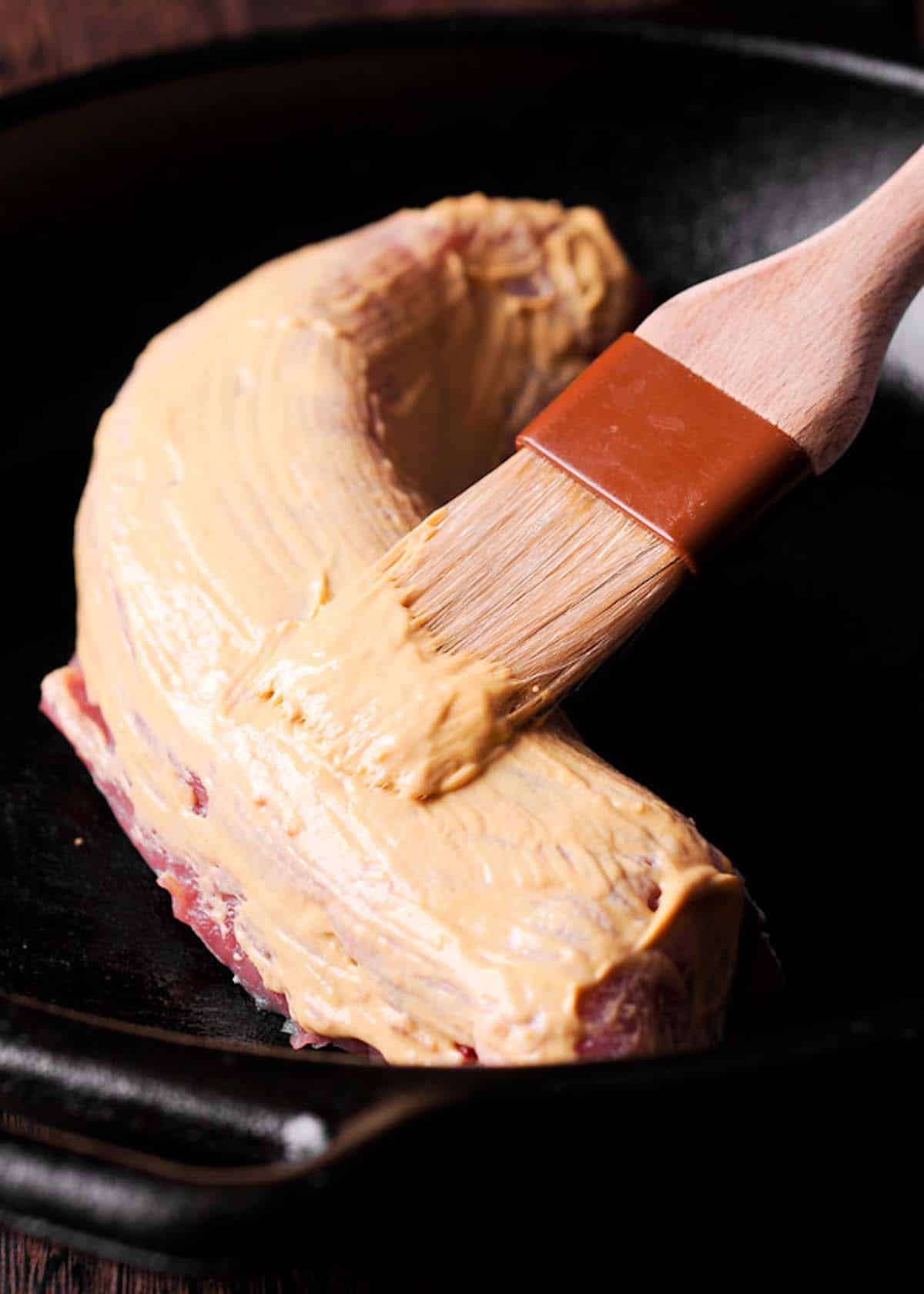 Pork tenderloin covered with mustard with a brush