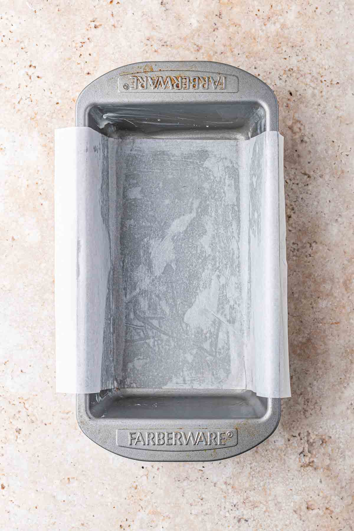 empty rectangular loaf pan with parchment paper in it