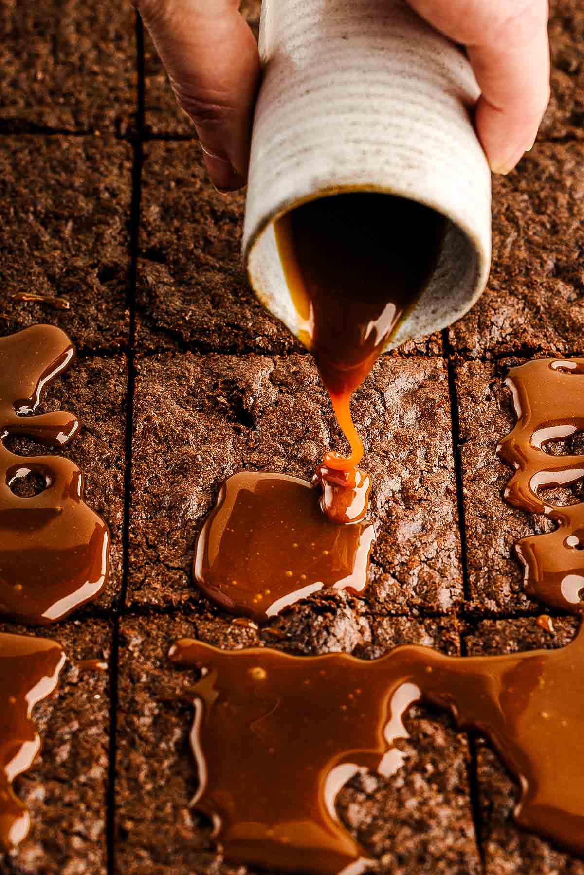 Pouring sated caramel sauce over the brownies