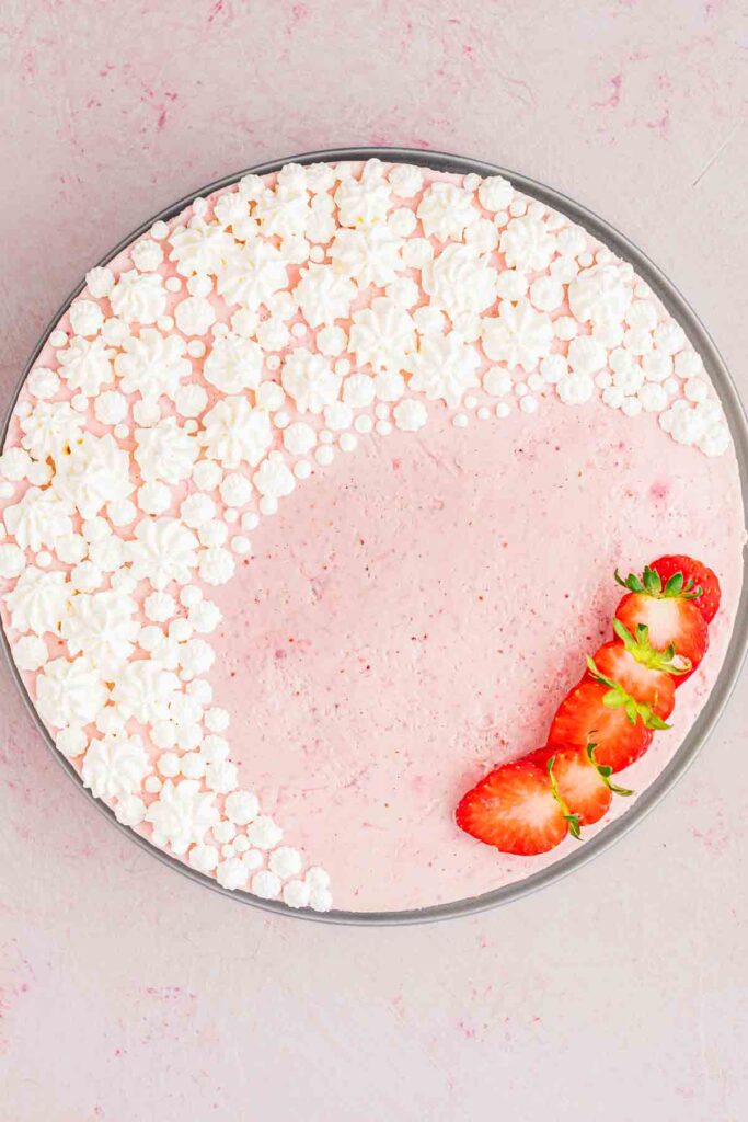 whipped cream piped on top of the strawberry gelatin mixture with fresh strawberries on the side