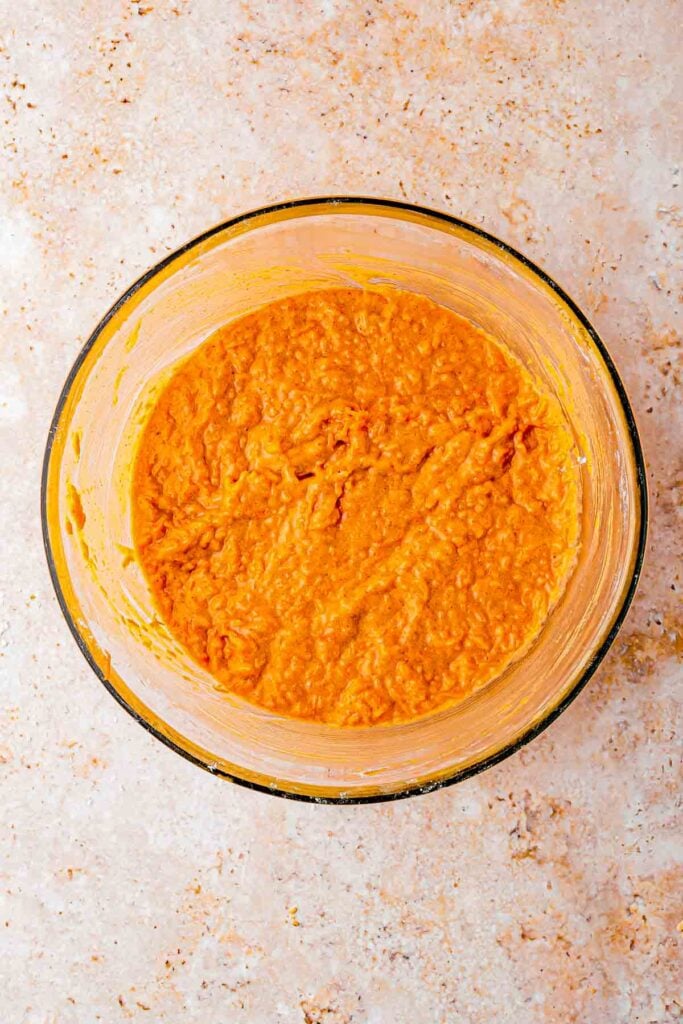 shredded carrots folded in the wet mixture with eggs in the bowl