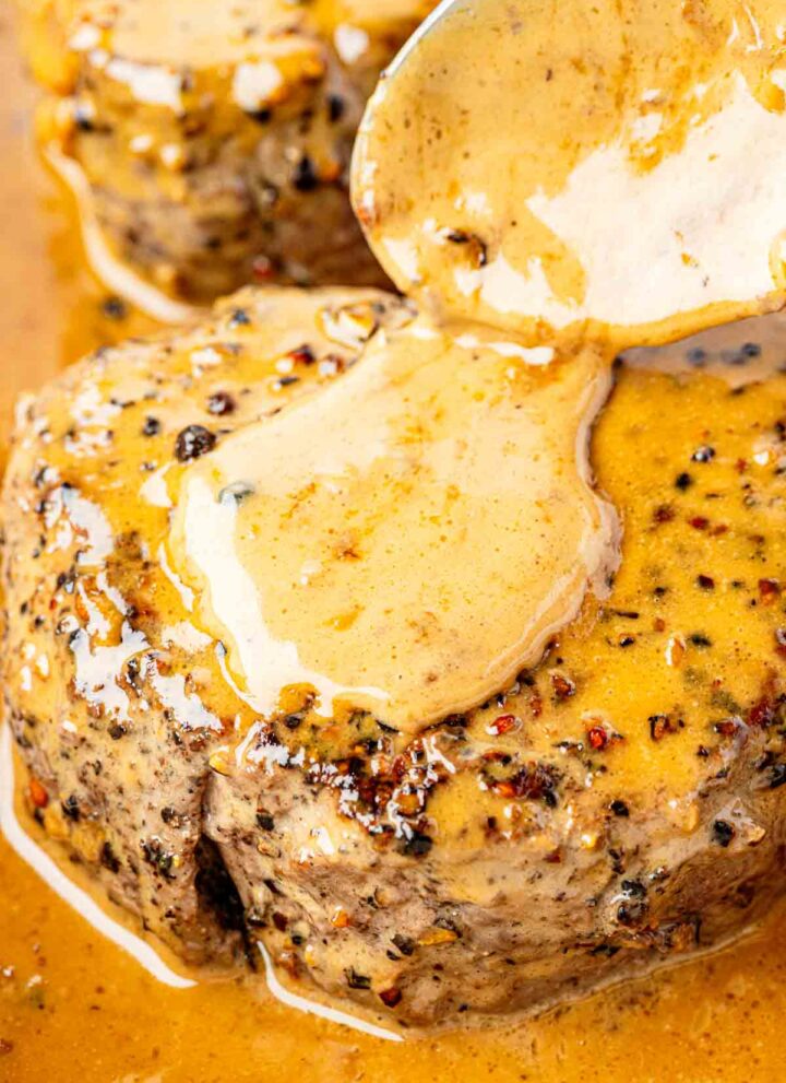 peppercorn steak with sauce being spooned on top