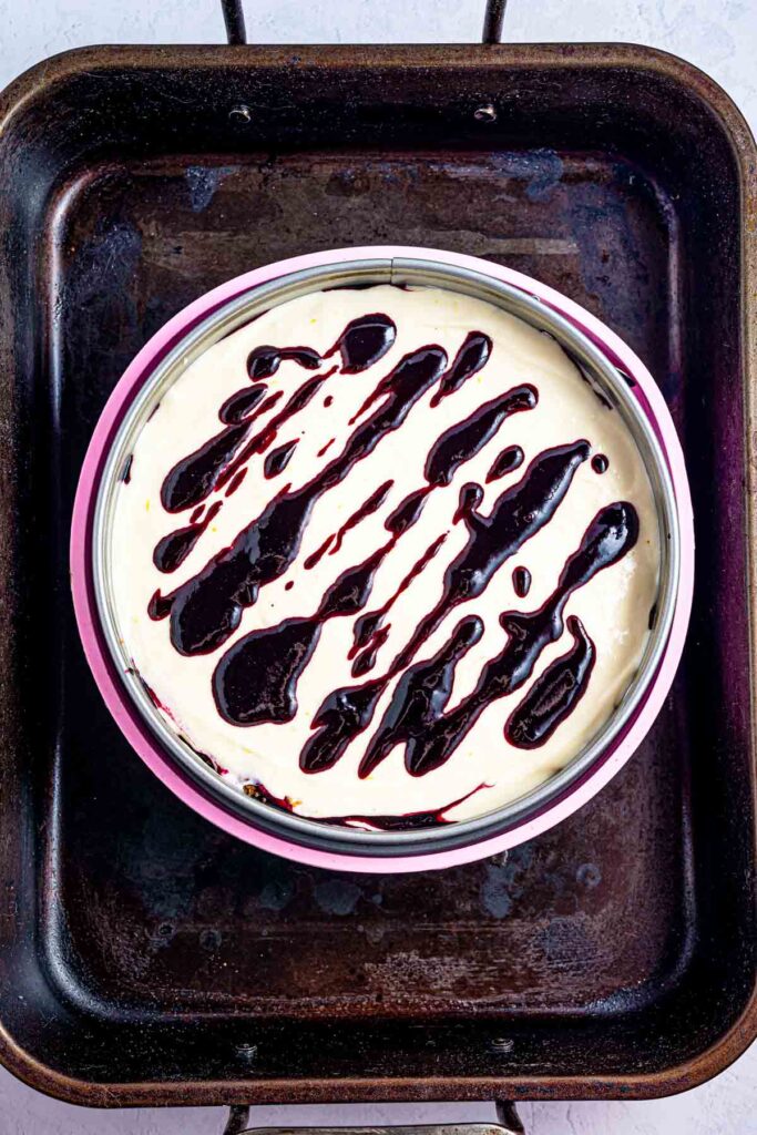 making blueberry streaks to start doing swirls on top of a lemon cheesecake