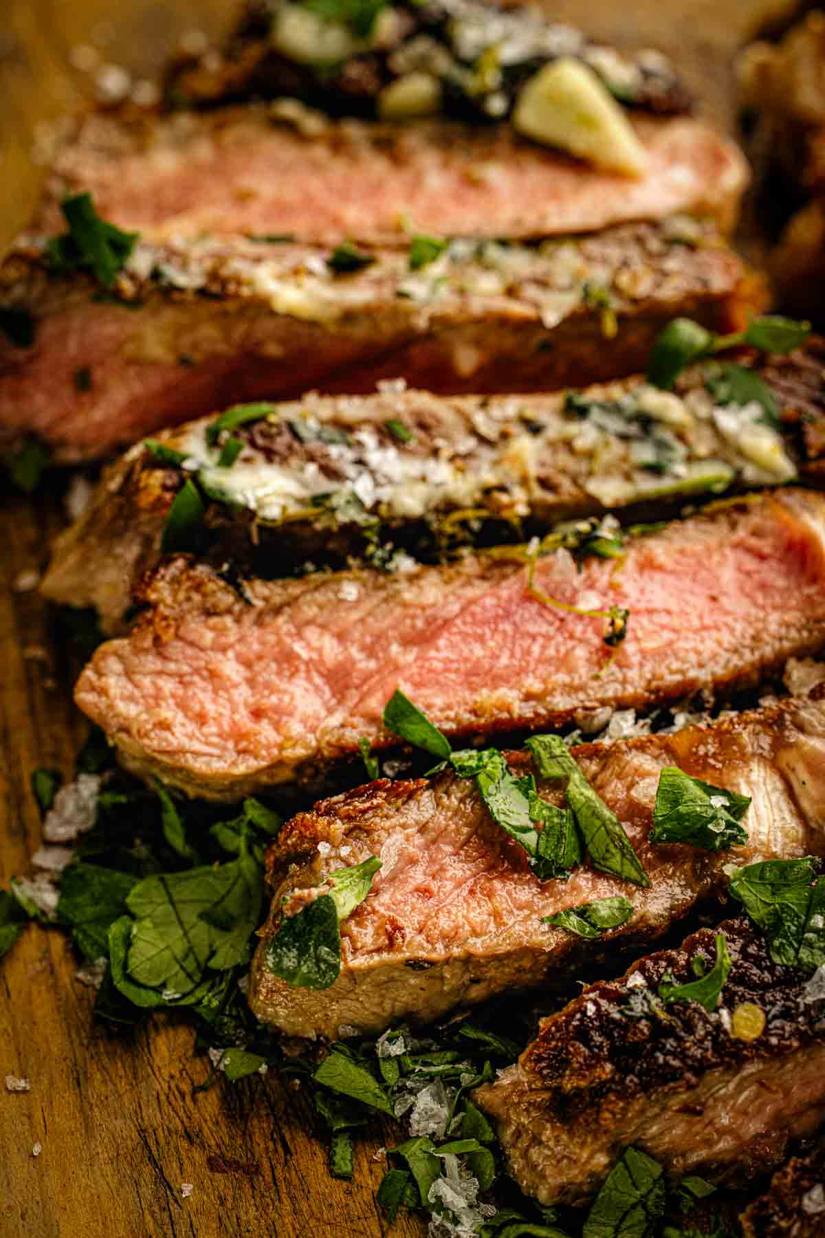 pan seared sirloin steak on cutting board with garlic butter sliced against the grain