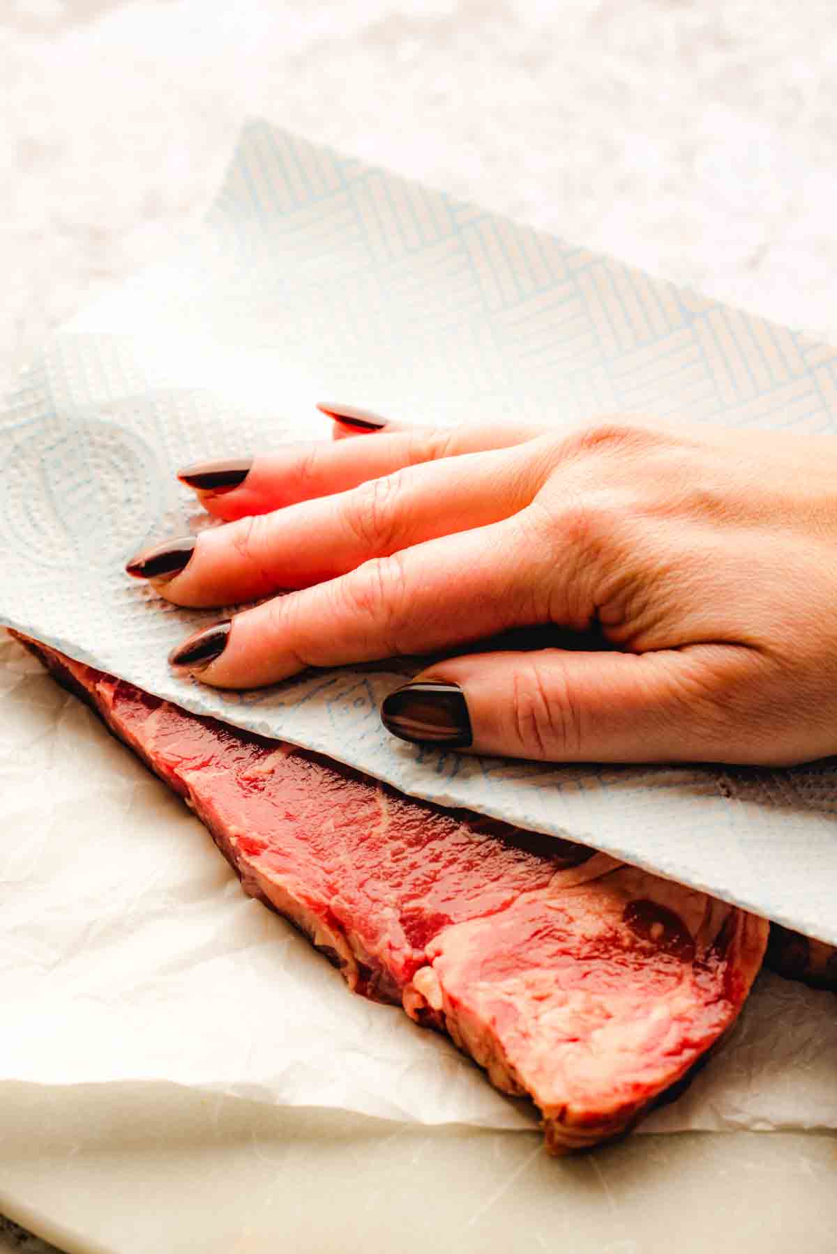 patting sirloin steak with the paper towels