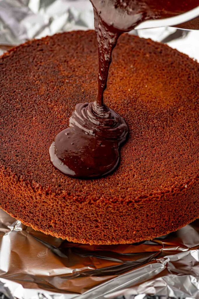 chocolate ganache glaze being poured on top of the brazilian carrot cake