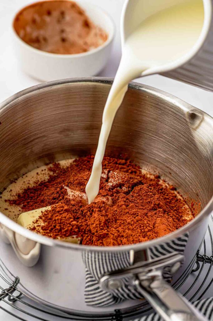 cream poured over the egg and chocolate powder in the bowl for the chocolate ganache glaze for the brazilian carrot cake