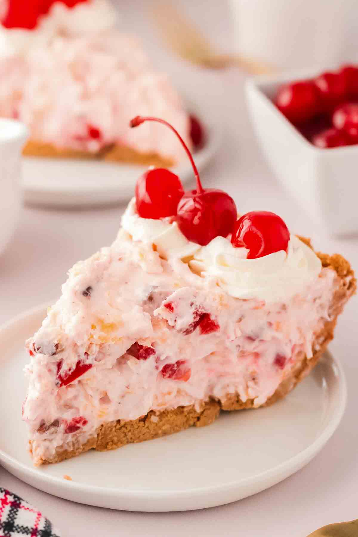 Slice of millionaire pie on a white plate showing creamy coconut pineapple and cherry filling