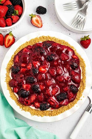 adding berry compote topping to cream cheese pie