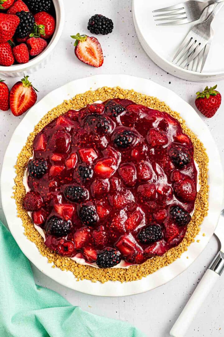adding berry compote topping to cream cheese pie