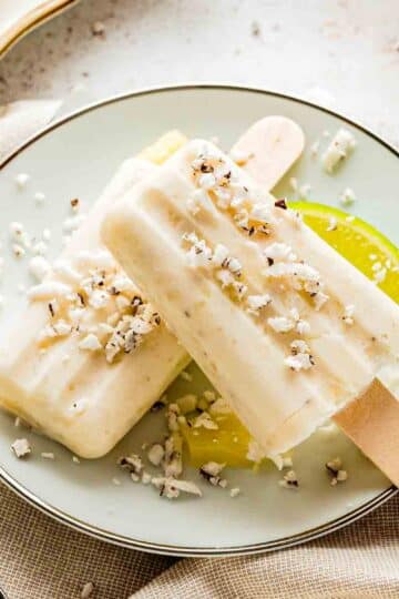 creamy tropical popsicles with shredded coconut on wooden surface