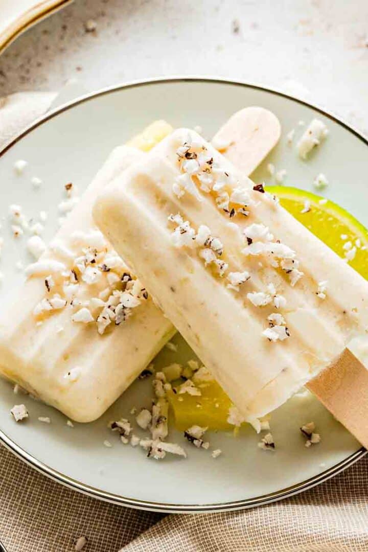 creamy tropical popsicles with shredded coconut on wooden surface