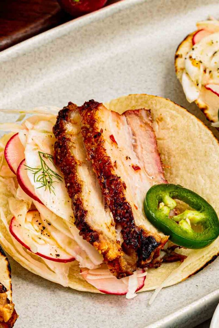 slow roasted pork belly tacos on corn tortillas with fennel radish slaw and sliced jalapenos