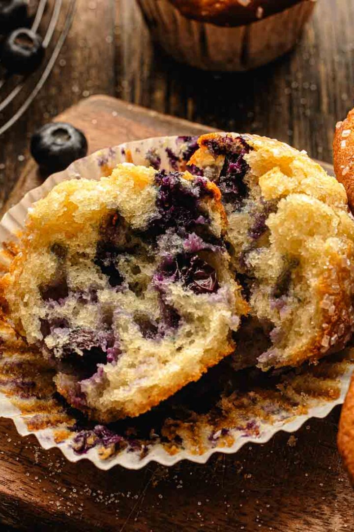 Single blueberry muffin on a small plate with a bite taken out showing moist interior crumb