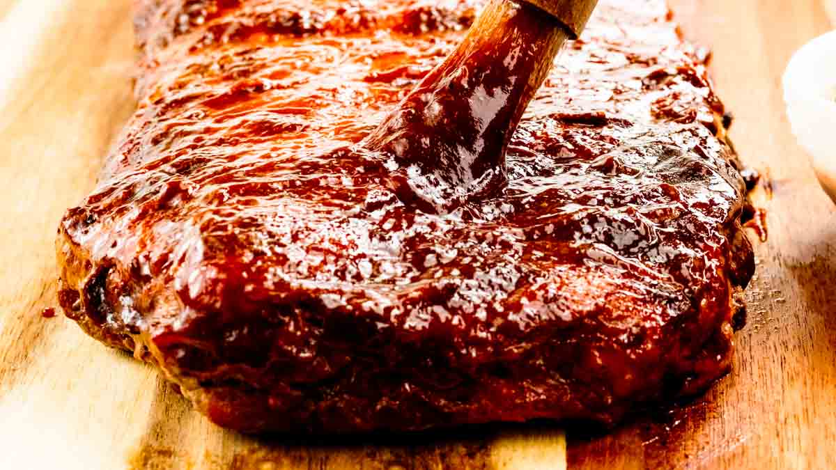 grilled ribs being brushed with bbq sauce