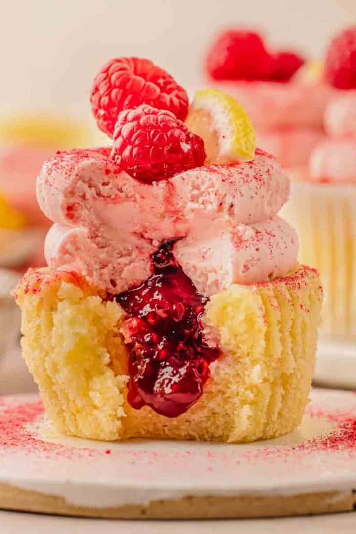 Lemon raspberry cupcakes with pink raspberry buttercream frosting topped with fresh raspberries and lemon slices"