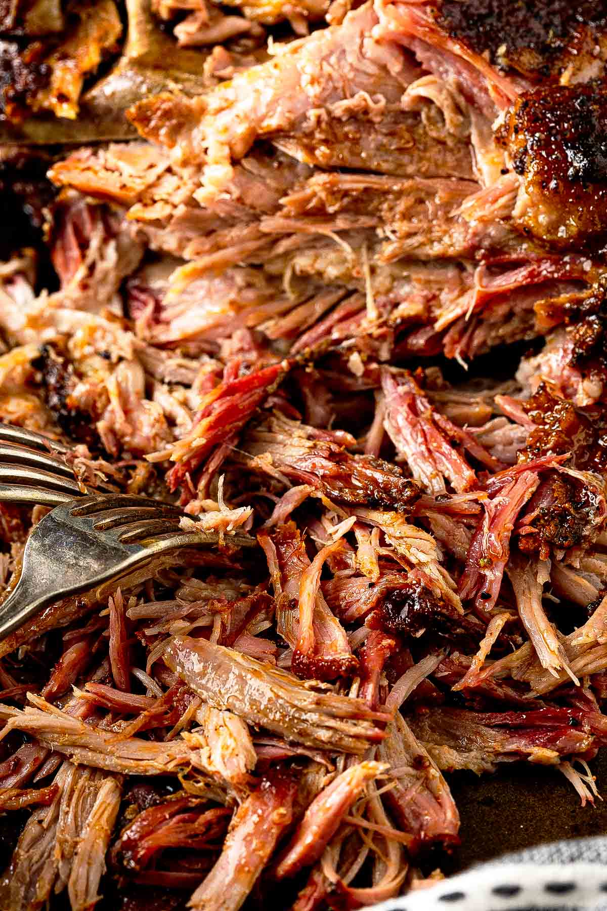 Close-up of smoked Boston butt with dark bark crust freshly pulled from the smoker and resting on foil