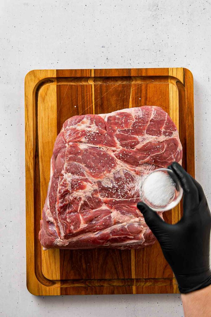 Kosher salt sprinkled evenly over all sides of a raw Boston butt on a foil-lined sheet pan