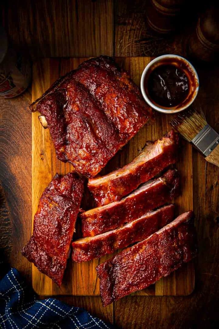 Close-up of smoked baby back ribs being pulled apart showing the tender meat releasing cleanly from the bone with a thick bark crust