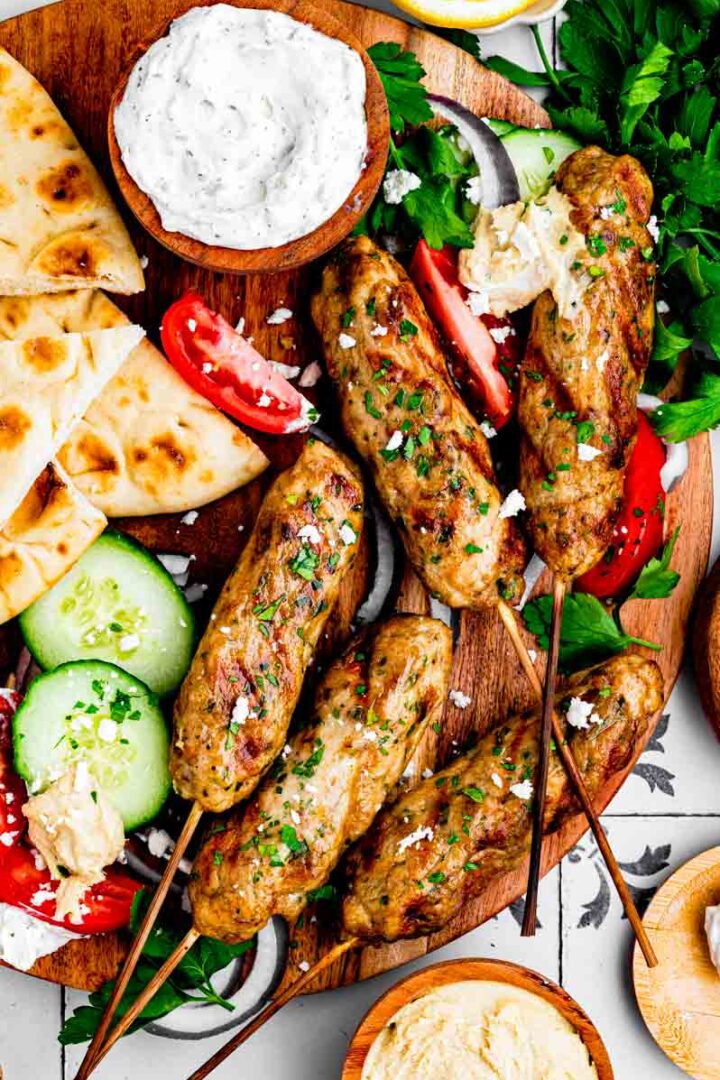chicken kofta on a cutting board surrounded by mezzo and sauces