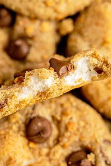 Stack of gooey s’mores stuffed cookies on a plate with melted chocolate and toasted marshmallow centers