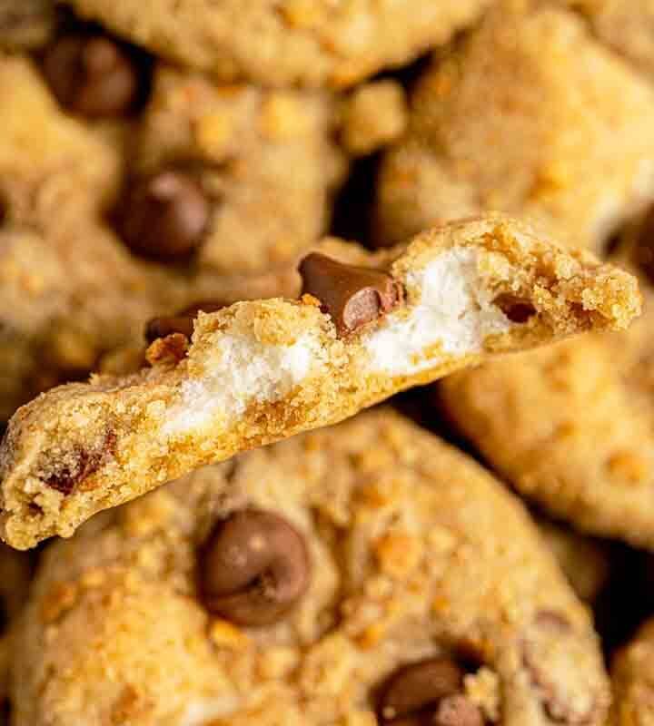Stack of gooey s'mores stuffed cookies on a plate with melted chocolate and toasted marshmallow centers