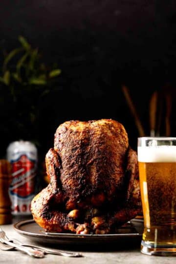 Smoked Beer Can Chicken in vertical position with a glass of beer in front of it