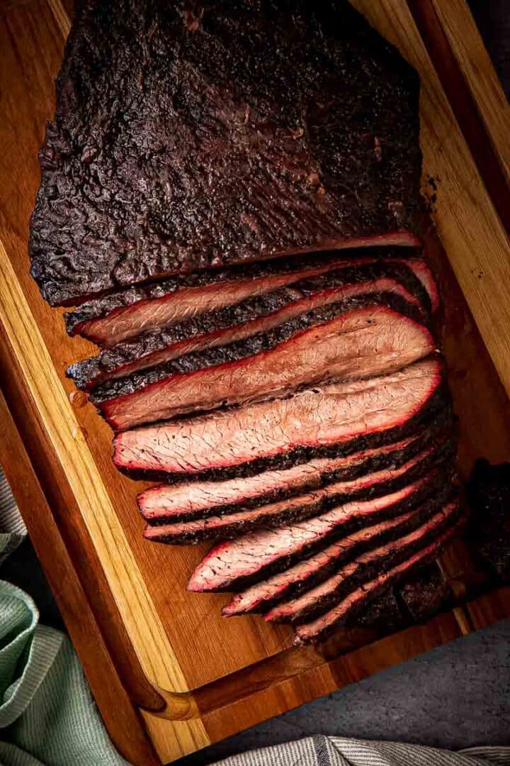 Sliced brisket flat on cutting board with dark crackling bark and juicy pink interior from pellet smoker
