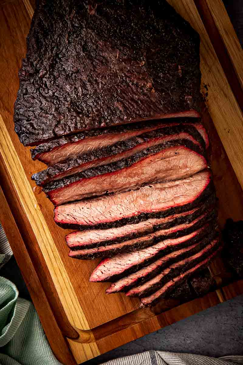 Sliced brisket flat on cutting board with dark crackling bark and juicy pink interior from pellet smoker