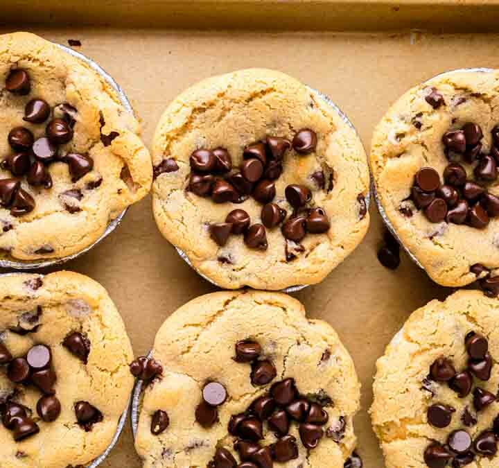 Overhead shot of six s'mores skillet cookies on baking sheet with extra chocolate chips pressed into tops