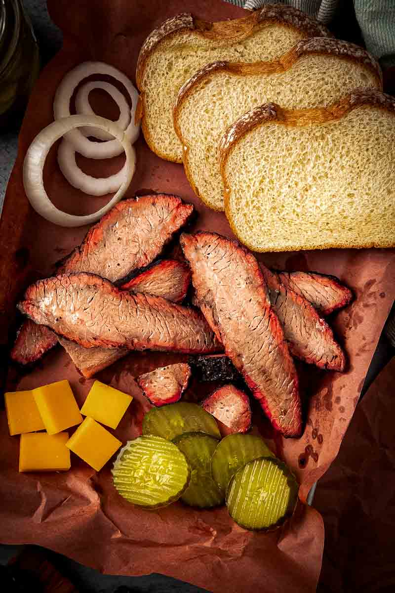 Thin slices of Texas-style brisket flat on a cutting board, highlighting bark, smoke ring, and glistening meat.