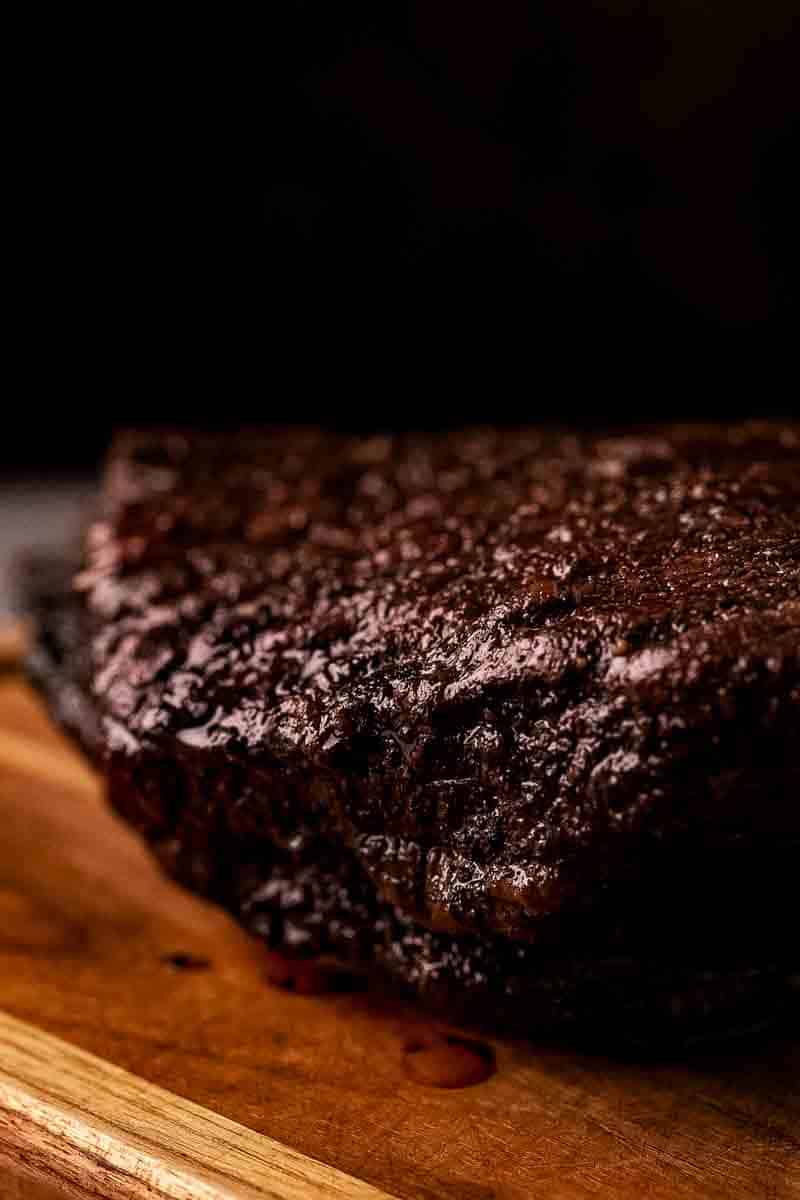 Fully rested smoked brisket flat arranged on a cutting board, showing juicy interior and dark peppery bark.