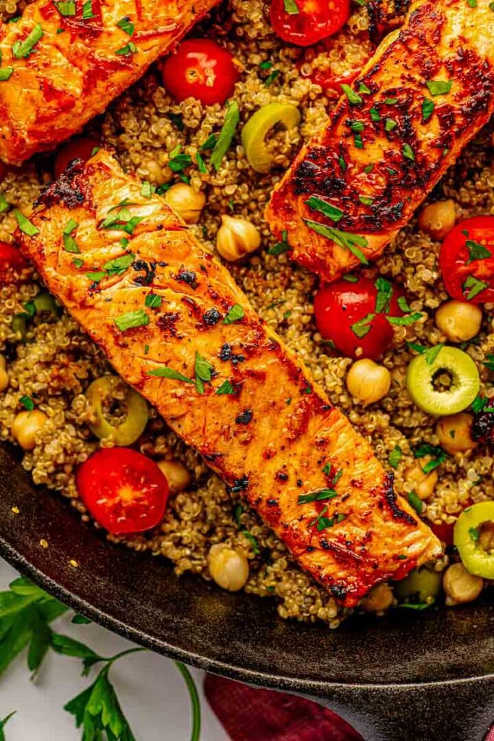 Plated harissa salmon over quinoa on a white dish, with a fork and lemon wedge ready for serving.