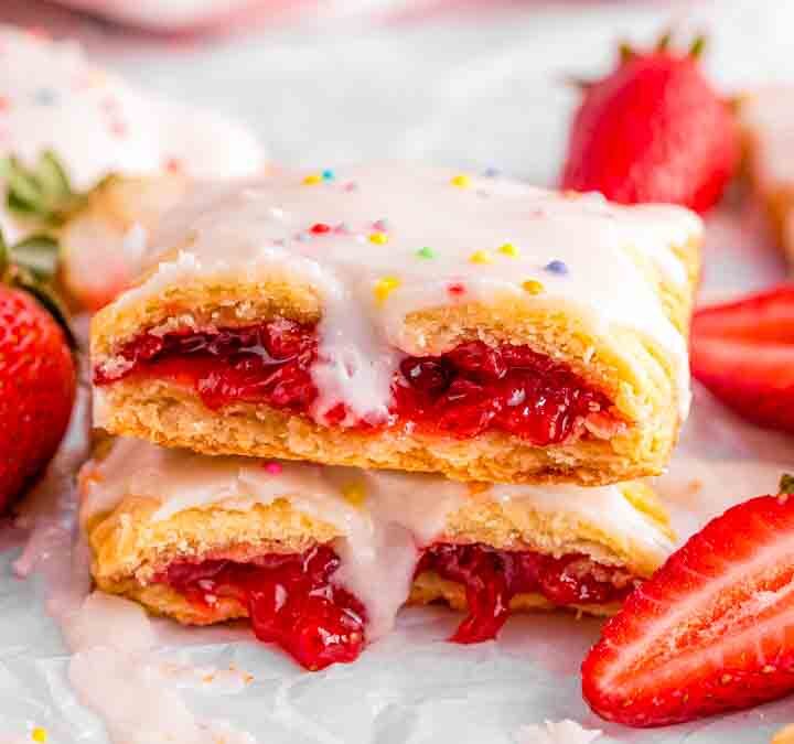 Golden baked strawberry pop tarts cooling on parchment paper before glazing.