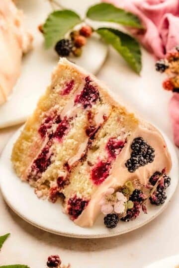 Single slice of blackberry layer cake plated, showing buttercream, jam filling, and cake layers