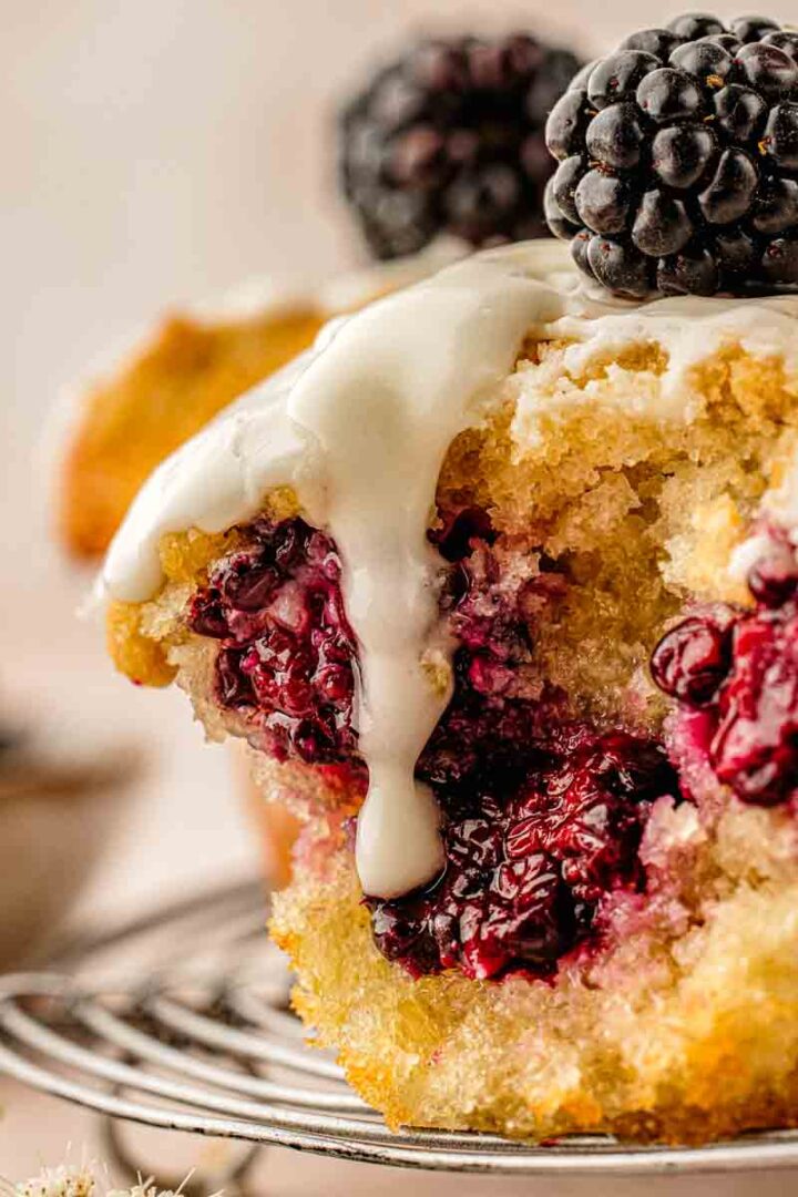 Blackberry crumb muffin cut in half, showing whole blackberries and moist yellow crumb inside
