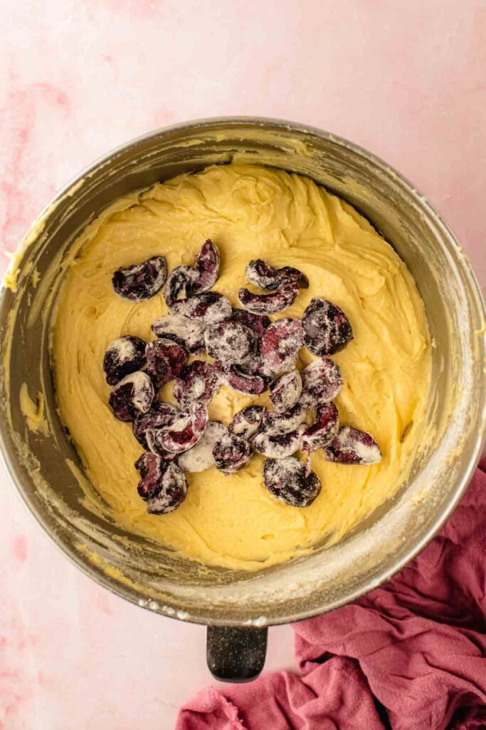 First layer of batter spread in a greased bundt pan before adding fresh cherries for a cherry bundt cake