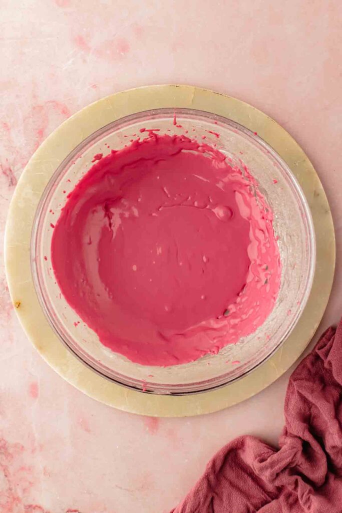 Cherry icing coating the back of a spoon, showing the right consistency before pouring over cherry bundt cak