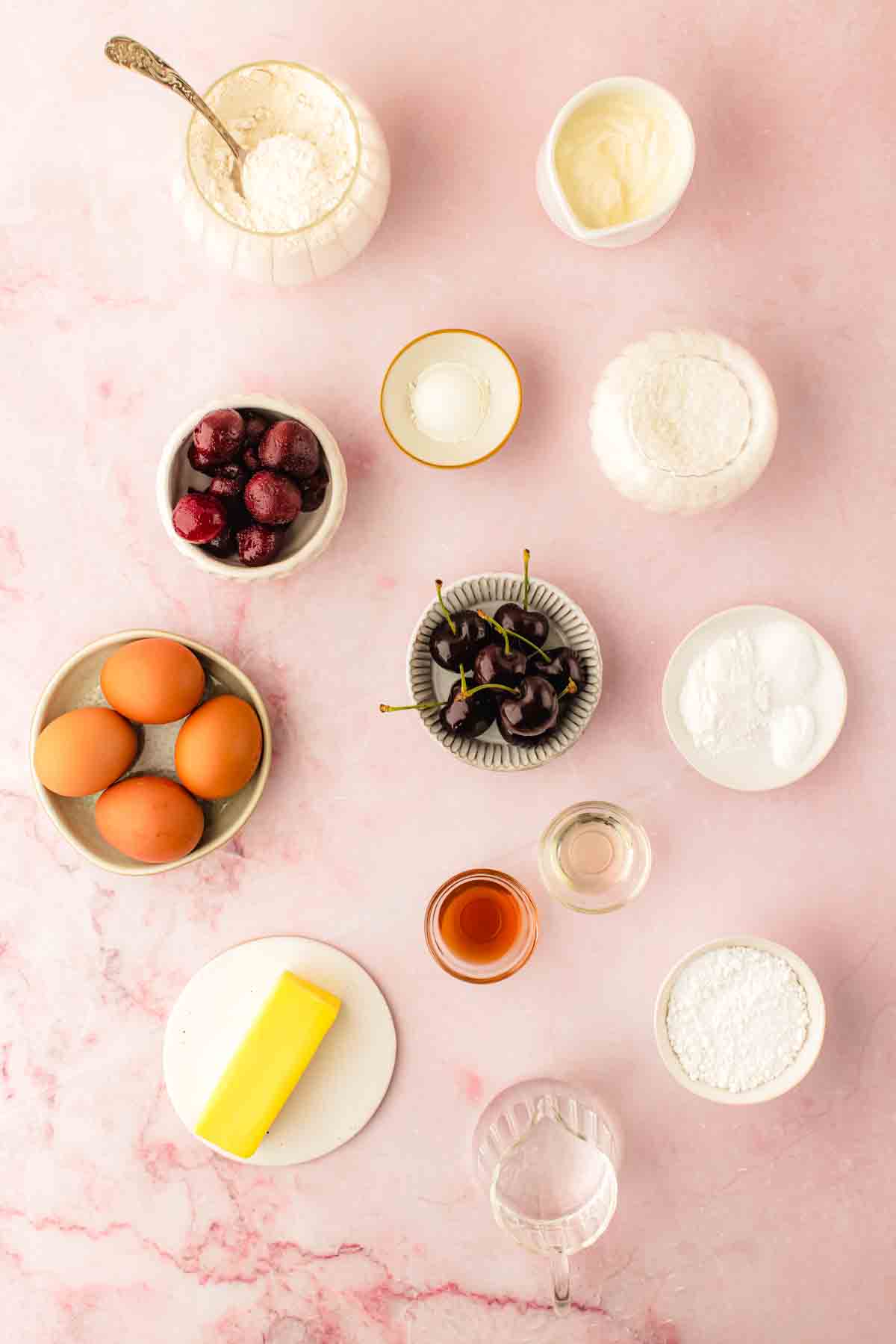 Ingredients for fresh cherry bundt cake laid out, including fresh cherries, sour cream, and frozen dark cherries for syrup