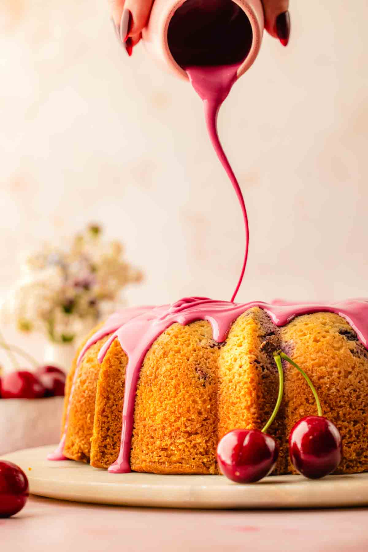 Pink cherry icing poured over a cooled cherry bundt cake, dripping naturally down the ridges