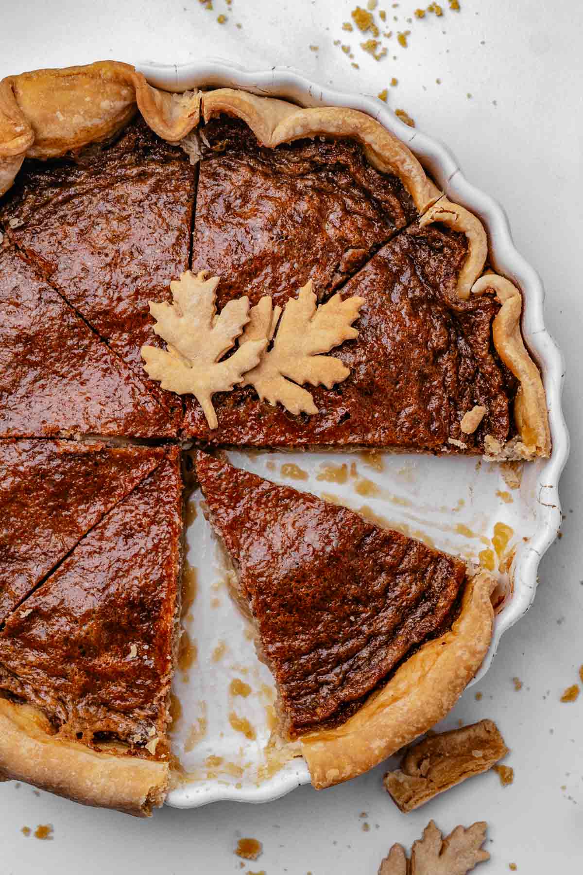 Sliced maple syrup pie showing a soft, custardy center and flaky pie crust Whole maple syrup pie with a golden, glossy top in a store-bought pie crust, cooling on a round pie dish
