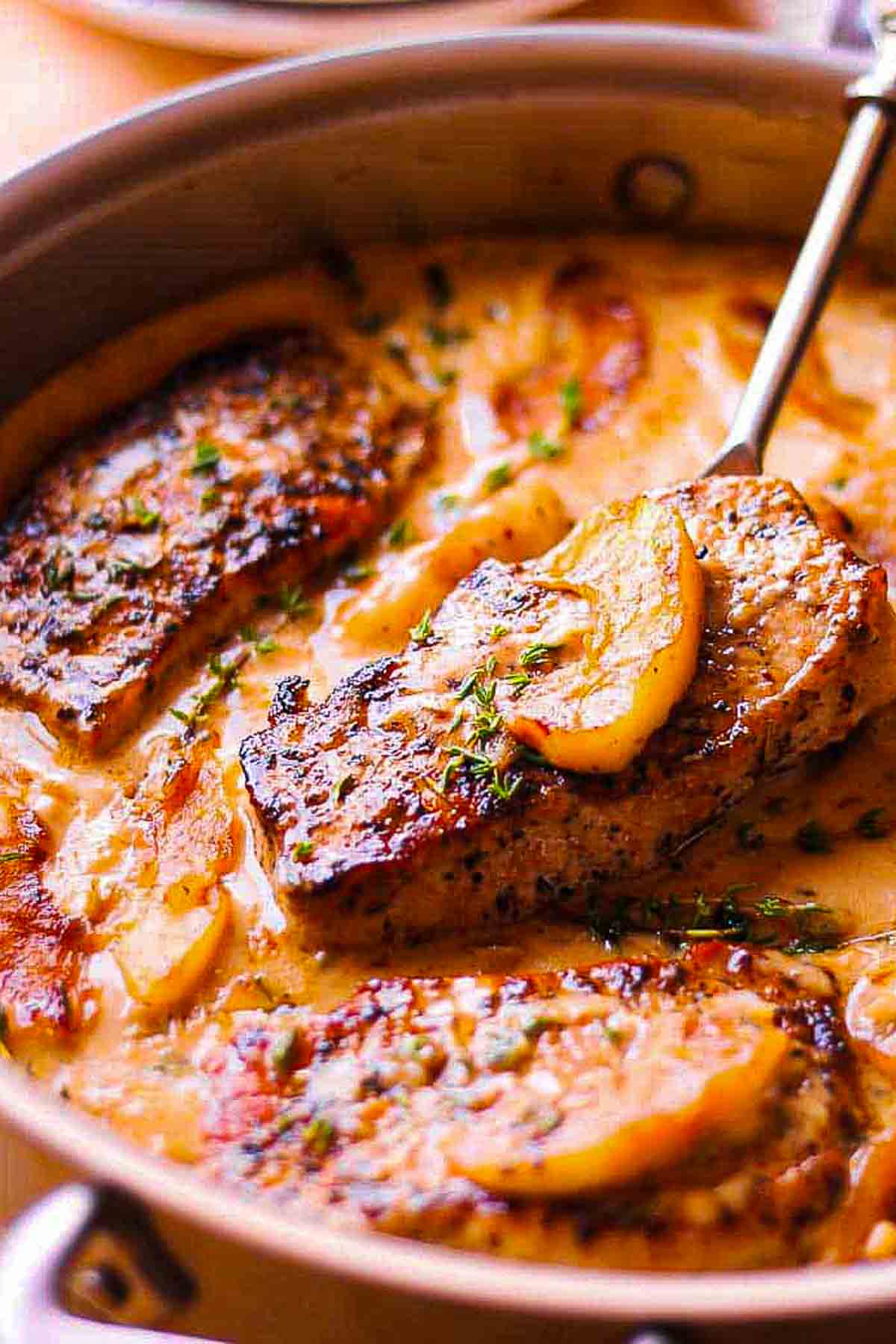 apple cider pork chops in the pan with creamy sauce and reduced apple cider sauce