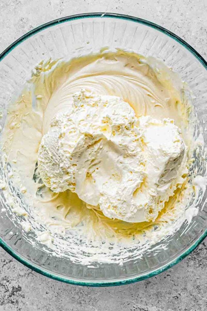 folded whipped cream topping inside the bowl with cream cheese mixture