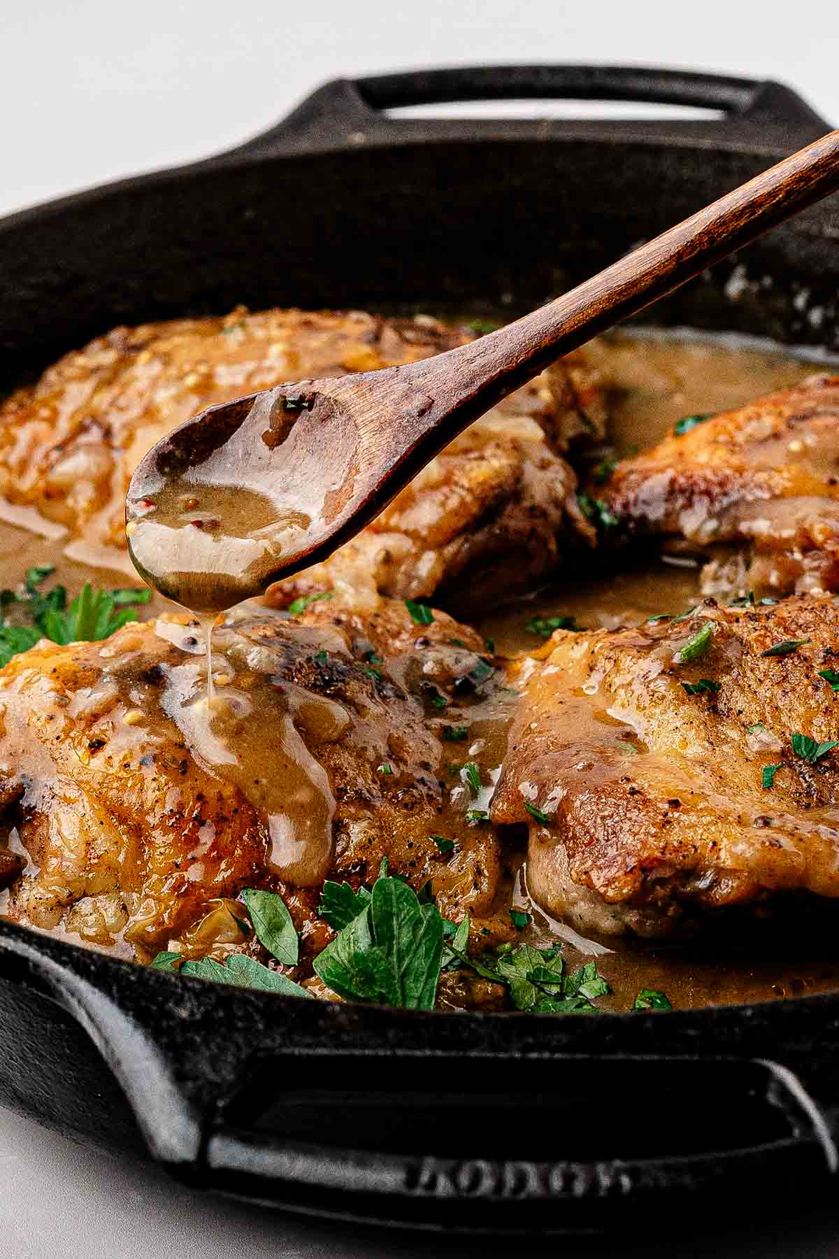 Close-up of crispy skin on a braised chicken thigh with a spoonful of beer sauce pooled underneath