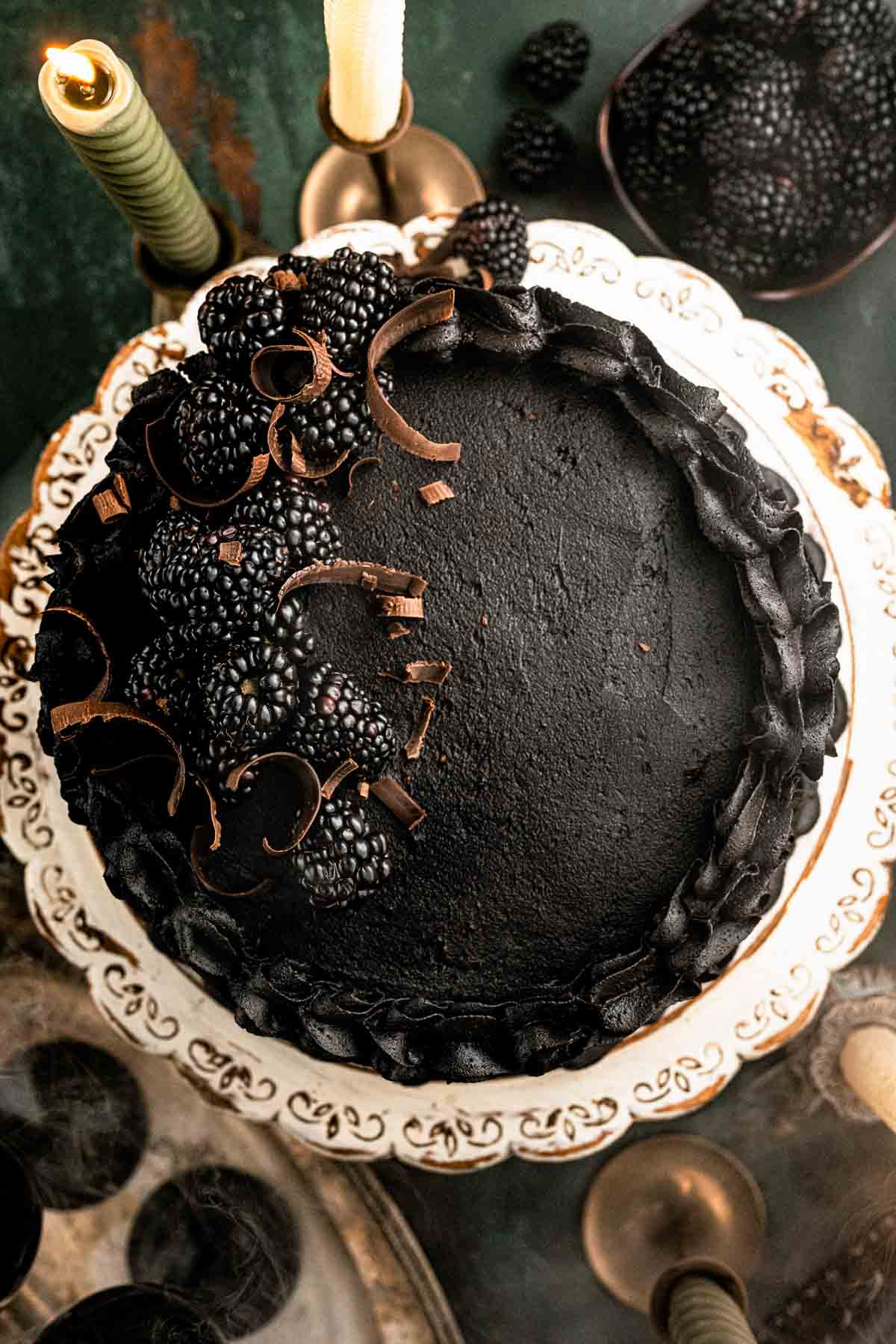 Overhead view of black velvet cake with piped buttercream swirls and blackberries