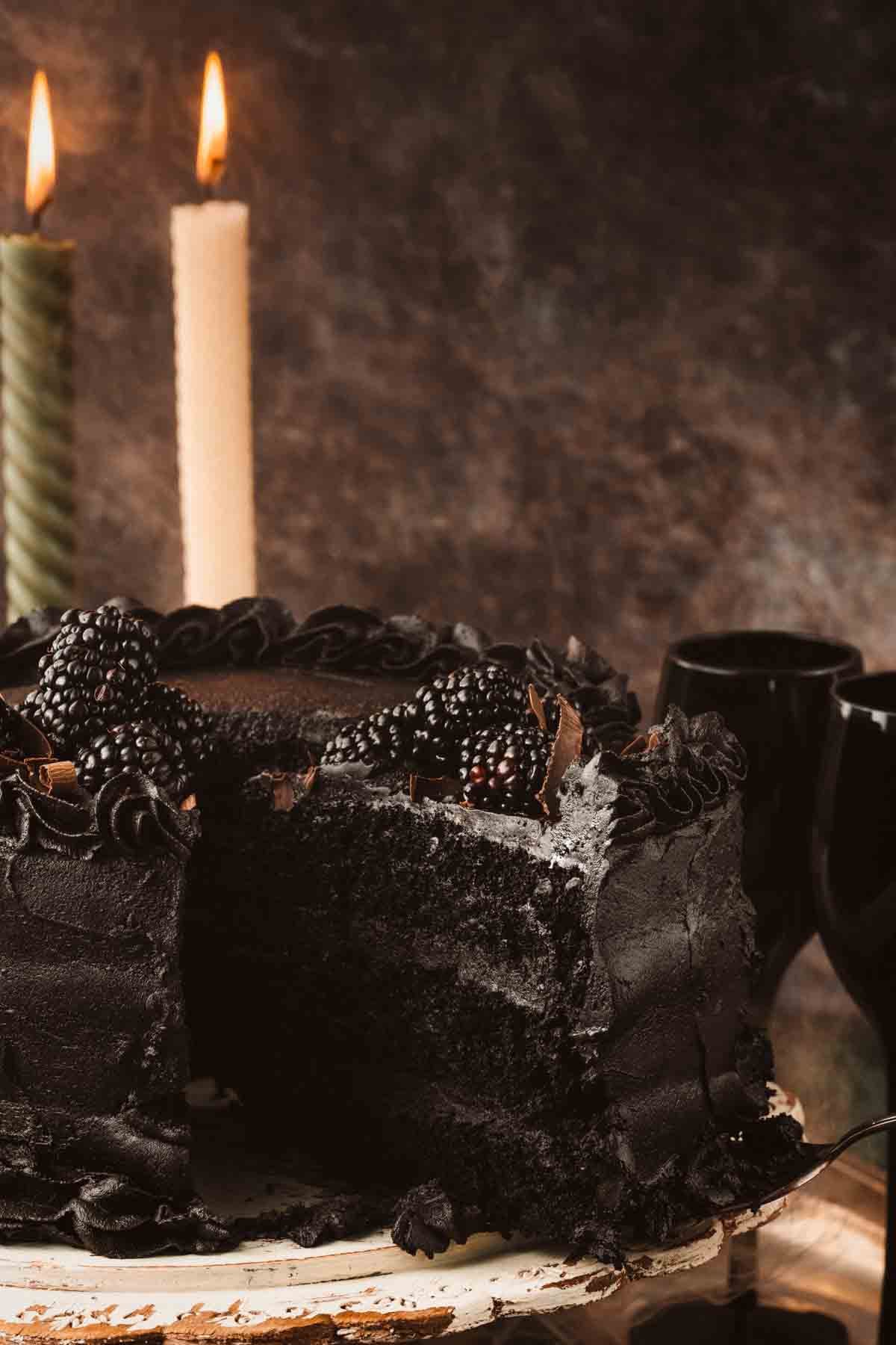 Slice of black velvet cake showing three moist, dark layers with black cocoa buttercream between them