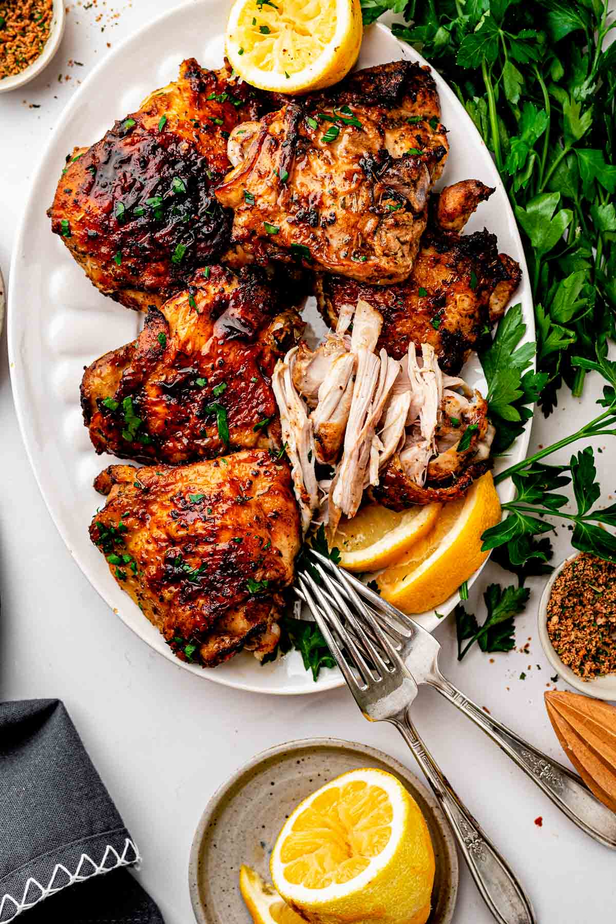 erving platter of dry rub chicken thighs with homemade lemon pepper rub, parsley and lemon wedges