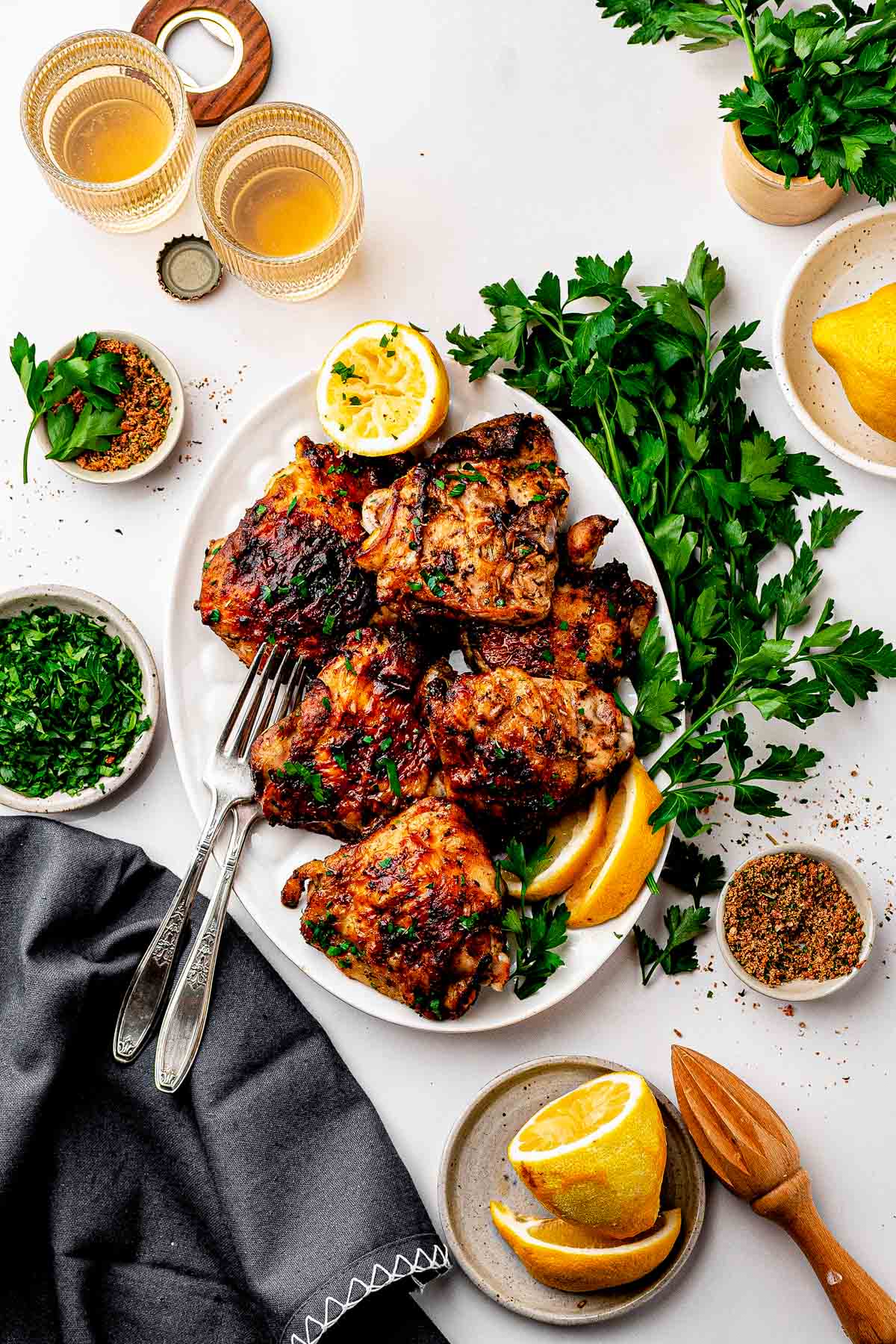 Overhead view of rispy dry rub chicken thighs with homemade lemon pepper rub on a sheet pan with lemon wedges and parsley